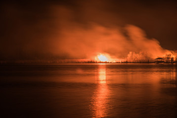 Naklejka na ściany i meble Night forest fire, reflected on the water surface of the river