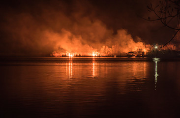 Night forest fire, reflected on the water surface of the river