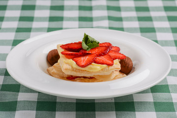 Cake of puff pastry with strawberry. Tasty delicious sweet Italian dessert with strawberry, cream served in white plate