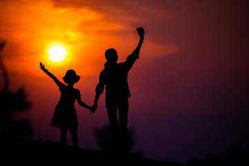 silhouette of a family with a happy mother playing with a girl in the sunset sky