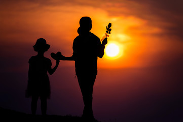 Naklejka premium silhouette of a family with a happy mother playing with a girl in the sunset sky