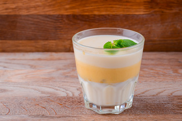 Fresh yogurt and lemon dessert. Fruit panna cotta in a glass over rustic wooden background. Copy space banner.