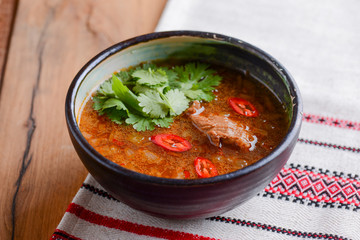 Traditional Ukrainian beetroot soup - borscht or borshch with meat and fresh green parsley over wooden background.
