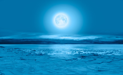 Night sky with full moon in the clouds  - Ice on the ocean shore at night "Elements of this image furnished by NASA"