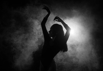 Female silhouette dancing in shadow and smoke - obrazy, fototapety, plakaty