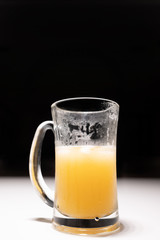 Tall glass with a handle and half a amber beer There is a drop of water on the side of the glass from the coldness. On a white table with black background Dark tone image