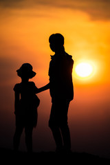 Fototapeta na wymiar silhouette of a family with a happy mother playing with a girl in the sunset sky