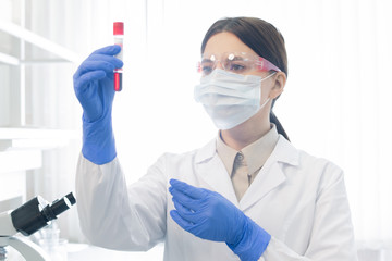 Naklejka premium Young female scientist or chemist holding flask with liquid substance