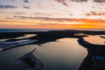 Aerial drone image of Rottnest Island lakes at sunset. The golden light covers the island and the lakes light up, reflecting the clouds. 