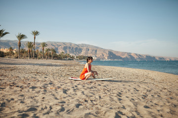 Fototapeta na wymiar Young woman in the beach with her surf table waiting in the sand