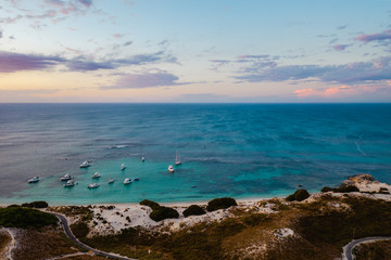 Aerial drone shot of a magical sunset over Rottnest Island, Perth, Western Australia. Geordie Bay below with luxury boats and yachts. 