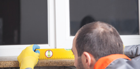 Obraz premium Caucasian worker holding measuring level of a window.