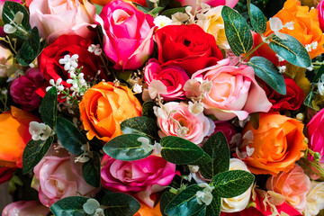 Artificial rose flower bunch background. Various colorful fake rose flower bouquet with leaves