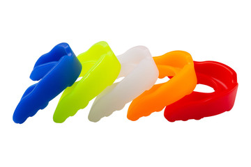 many multi-colored boxing mouth guards, lie in a row, on a white background