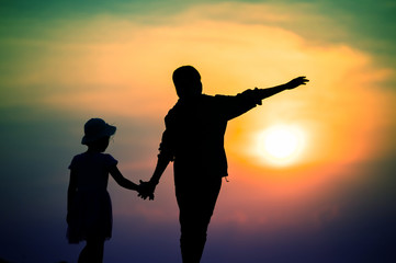 Fototapeta premium silhouette of a family with a happy mother playing with a girl in the sunset sky