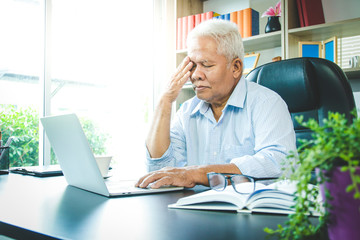 The elderly Asian man sat in the office. He has stress and is sick. Retirement concept, senior...