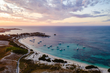 Aerial drone shot of a magical sunset over Rottnest Island, Perth, Western Australia. Geordie Bay below with luxury boats and yachts. 