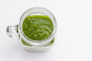 glass jar glass with green fresh smoothie and raw vegetables on white background