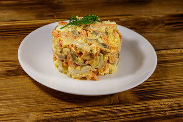 Tasty salad with chicken breast, roasted mushrooms, carrots, grated cheese, eggs and mayonnaise on wooden table