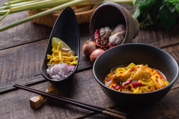Thai noodles chicken curry in black bowl.