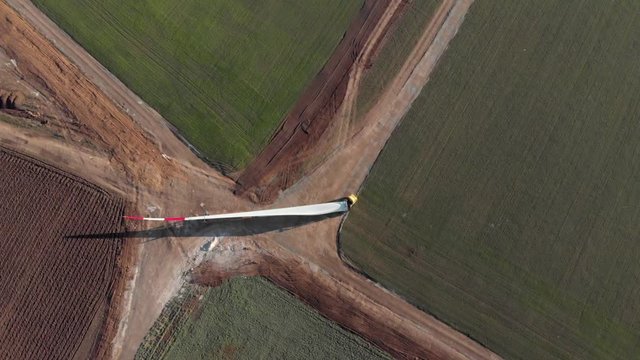 Building process of wind energy power tower mill, under construction. Transportation, installation of rotor blades. Green, clean, renewable energy. Aerial footage.