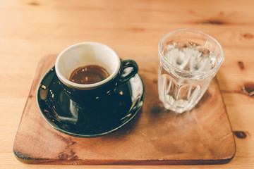 Set of espresso coffee cup with a glass of water on wooden table.