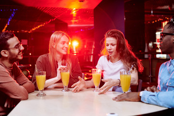 Two young intercultural couple sitting by table in cafe at leisure center