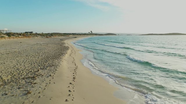 Aerial video flying over the shore of the Illetas beach in Formentera,
approaching woman lying on the sand.
