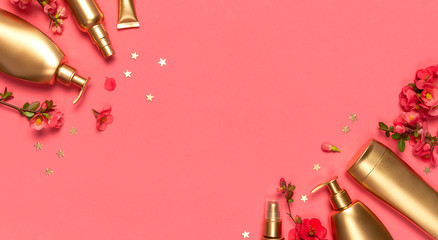 Cosmetics Branding Concept. Cosmetics, spring pink flowers, gold stars confetti on pink background. Cosmetic mock up gold bottles. Flat lay top view copy space. Cosmetic products, beauty background