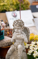 Kleiner Engel spielt auf der Panflöte auf einem Friedhof in Spanien