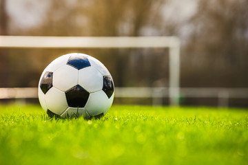 Classic soccer ball in sunset  with typical black and white pattern, placed on stadium turf....