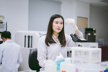 young female medical  scientist looking at test tube in medical laboratory 