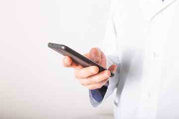 The concept of helping mobile devices in the provision of medical services. Doctor works in a phone on a white background. Copy space