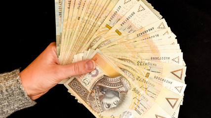 polish zloty currency, hand holding polish zloty cash on the black background