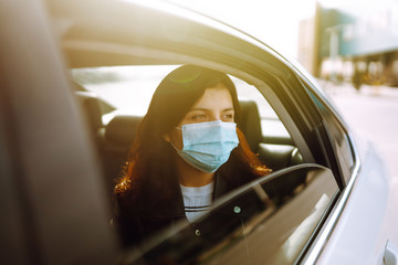 Girl in protective sterile medical mask on her face is sitting in a taxi. The concept of preventing...