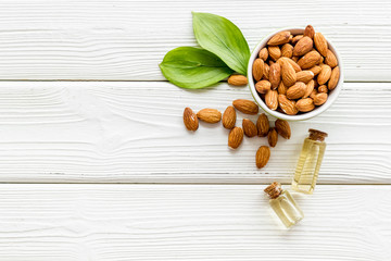 Skin care cosmetics. Almond oil in small bottles on white wooden background top-down copy space