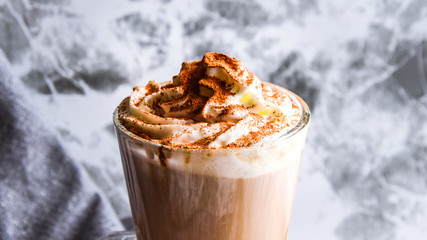 Hot latte macchiato coffee with caramel on tabletop outdoors. Natural hard daylight. Soft focus