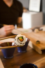 piece of a sushi holding with chopsticks