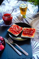 Sweet breakfast with freshly made jam on toast and a very hot tea or honey camomile served by a girl. She also spreads the jam