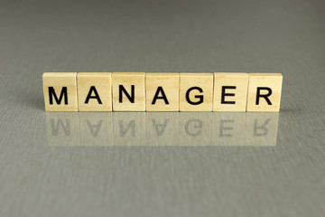 word Manager is made of square wooden letters on a gray background