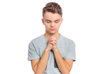 Portrait of teen boy praying, isolated on white background. Cute caucasian teenager with hands...