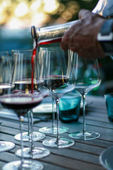 Man pouring red wine into glasses.