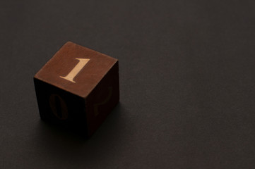 A single wooden die on dark gray background showing lucky number 1. Dice on background.