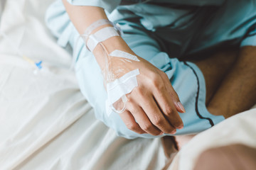 Hospital patient hand with saline solution in Intravenous Drip Dropper in hospital.