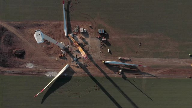 Building process of wind energy power tower mill, under construction. Transportation, installation of rotor blades. Green, clean, renewable energy. Aerial footage.