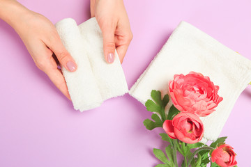  Beautiful young woman's hands with  white care  towel   on pastel pink background .