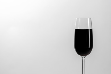 An empty glass with a black liquid on a white background. Minimalism. Isolated