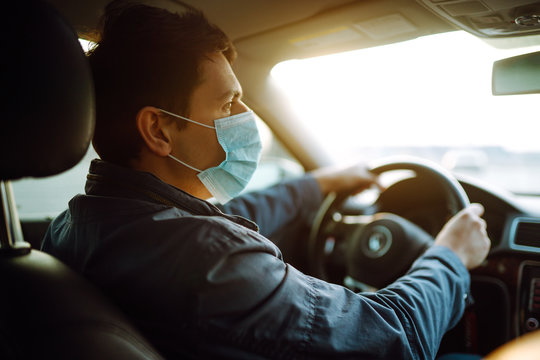 Young man in protective sterile medical mask driving car. The concept of preventing the spread of the epidemic and treating coronavirus, pandemic in quarantine city. Covid -19.