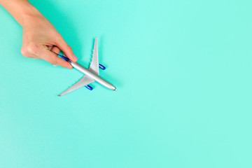 Beautiful young woman's hands holding plane    on pastel  background .