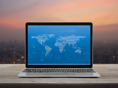 Global business words world map with modern laptop computer on wooden table over blur of cityscape on warm light sundown, Global business online concept, Elements of this image furnished by NASA